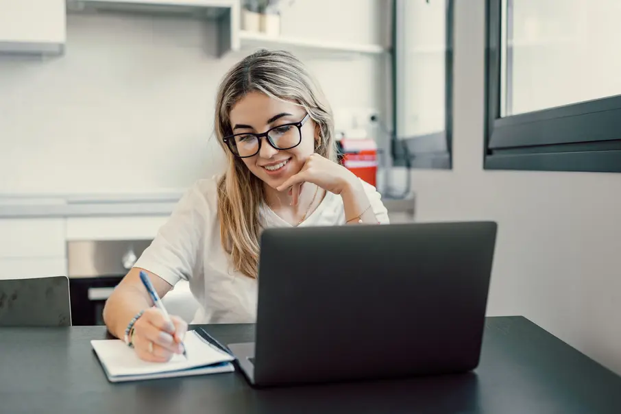 Happy online language student taking notes - Polymates academy Happy online language student taking notes - Polymates academy